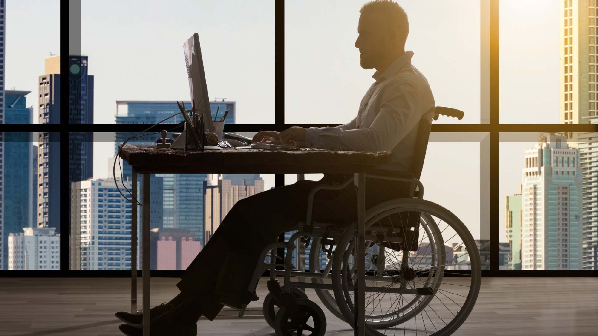 Man in wheelchair working on laptop in office